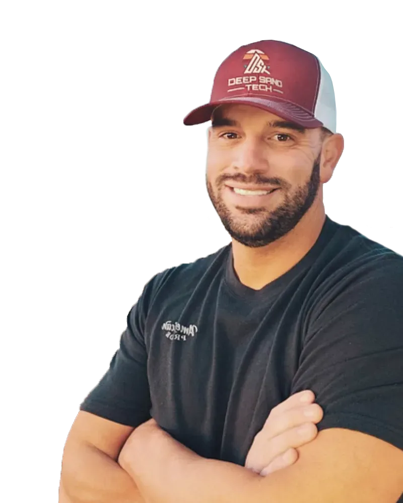 Man smiling, wearing a maroon and white cap, arms crossed. Dark shirt with logo.